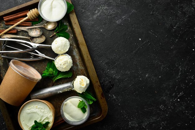 Vanilla sweet ice cream with mint Ice cream spoon On a black stone background top view