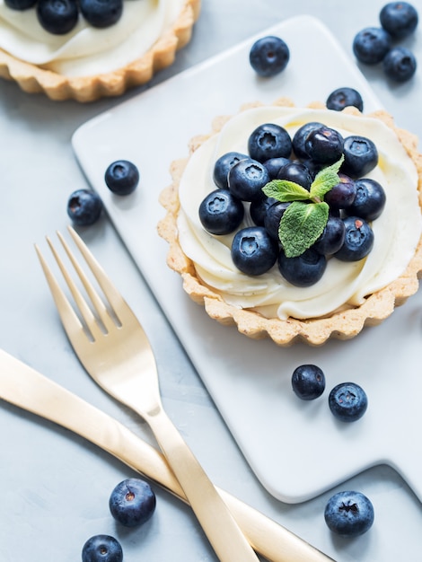 Vanilla tartlets with blueberry berries and gold cutlery