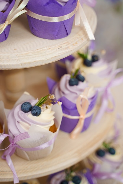 Vanille cupcakes met lavendelcrème. thematische muffins. cupcakes met room in de vorm van een papieren tulp, versierd met bosbessen, rozemarijn, bloemen, vastgebonden met een lint.