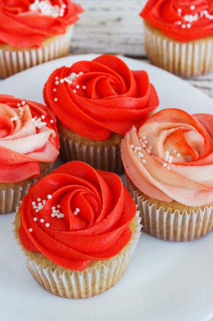 Vanille cupcakes versierd met een rode roos van een crème op een witte achtergrond