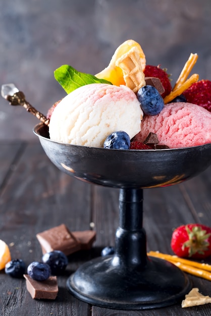 vanille en aardbei op smaak gebrachte bevroren dessert ijs in een metalen kom met bessen op houten