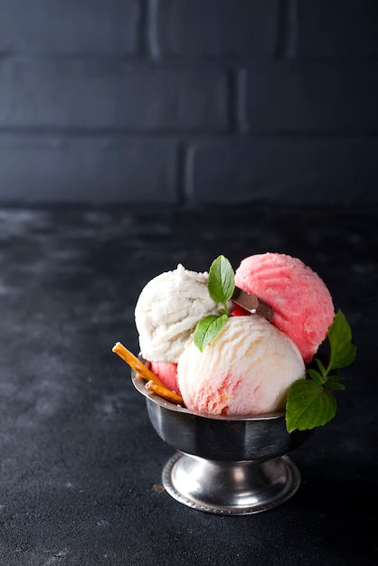 Vanille en roze ijs in een kom met bevroren bessen en wafelkegel
