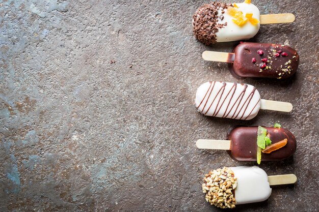 Vanille ijslollys met chocolade vacht en top met amandelnoten en snoepjes, bovenaanzicht.