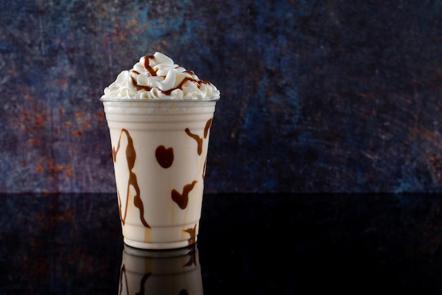 Vanillemilkshake met chocoladesiroop in helder glas op donkere achtergrond