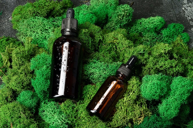 Vape smoking liquid bottles on moss background close up