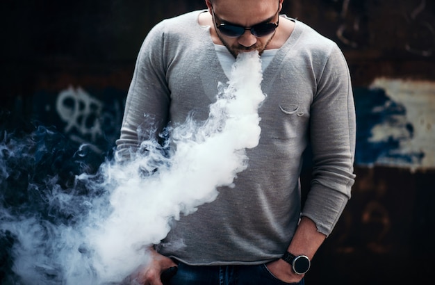 Vaper with beard in sunglasses vaping outdoor