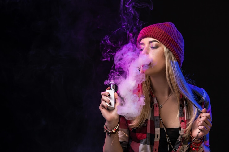 Фотография девушка вейпинга. молодая хипстерская женщина vape e-cig на студии на черном фоне. стиль хип-хоп. закройте вверх.