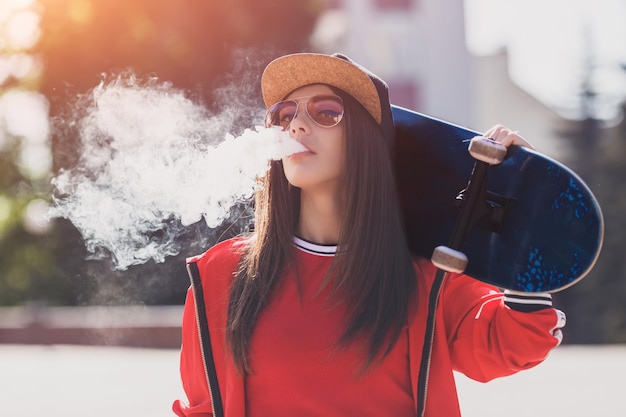 Vaping meisje jonge vrouw met skateboard vape ecig