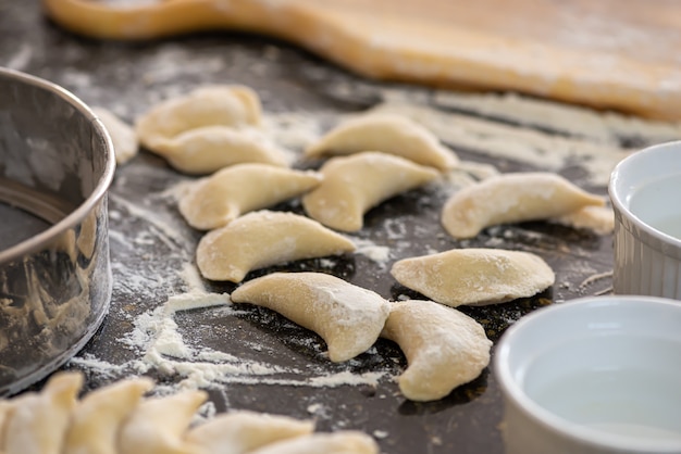 vareniki on cutting wooden board with flour.