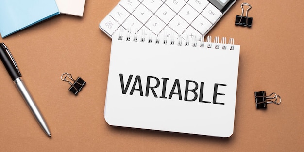 VARIABLE on notepad with pen, glasses and calculator