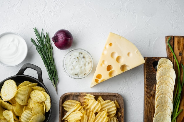 Variatie verschillende aardappelchips set met kaas en ui, met dipsauzen tomaat dip zure room, op witte stenen ondergrond, bovenaanzicht plat leggen