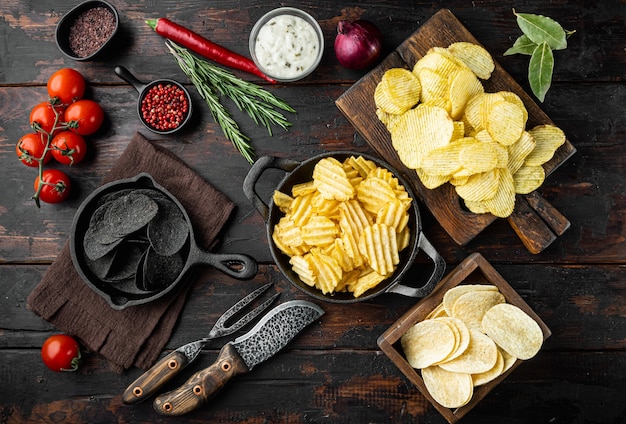 Variatie verschillende aardappelchips set, op oude donkere houten tafel, bovenaanzicht plat lag