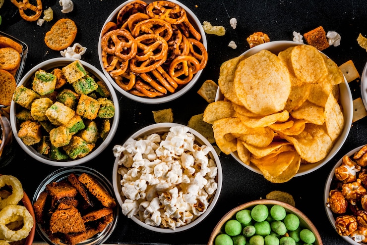 Foto variatie verschillende ongezonde snacks crackers, zoete gezouten popcorn, tortilla's, noten, rietjes, bretsels