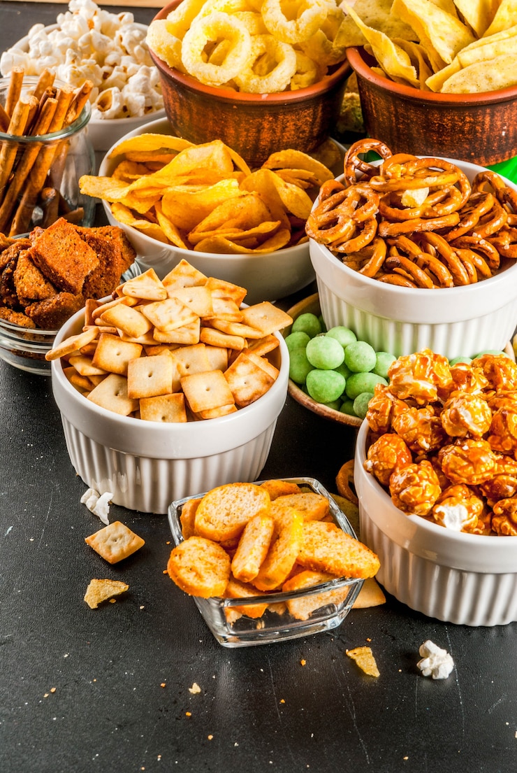 Foto variatie verschillende ongezonde snacks crackers, zoete gezouten popcorn, tortilla's, noten, rietjes, bretsels