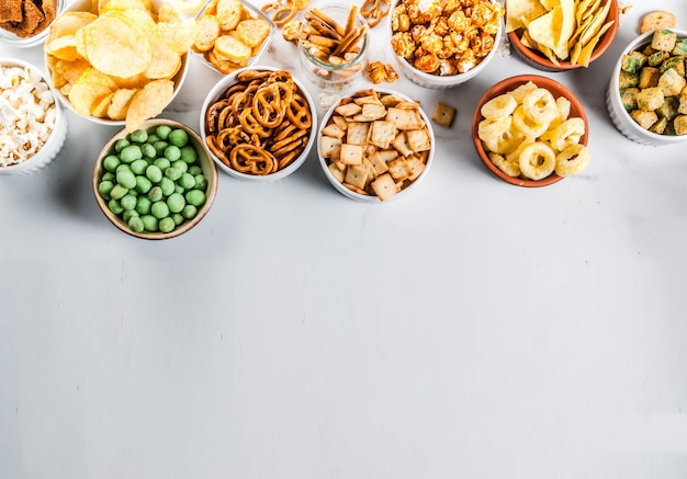 Foto variatie verschillende ongezonde snacks crackers, zoete gezouten popcorn, tortilla's, noten, rietjes, bretsels