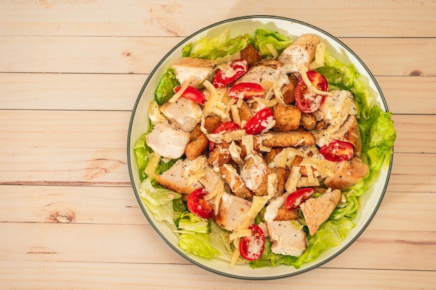 variation of Caesar salad with small bites of chicken cherry tomatoes and a aioli sauce in a bowl