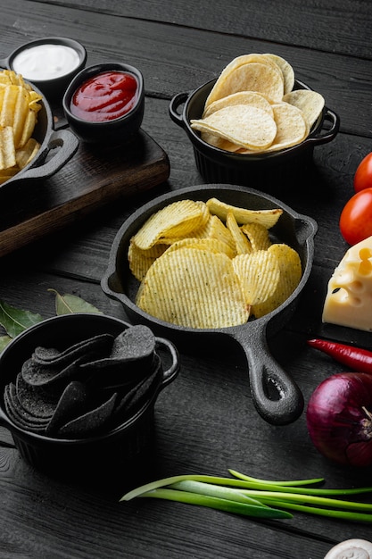 Variation different potato chips set, on black wooden table