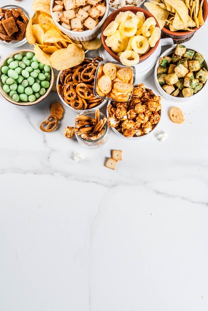 Variation different unhealthy snacks crackers, sweet salted popcorn, tortillas, nuts, straws, bretsels