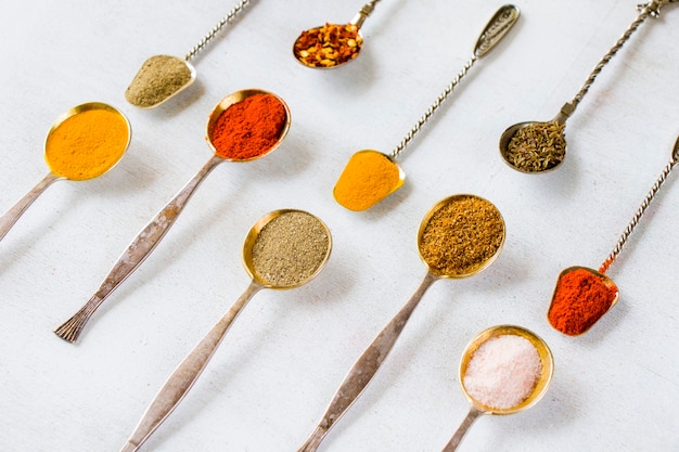 Variation of spices on the vintage silver spoons, all spices on the table, colorful food  