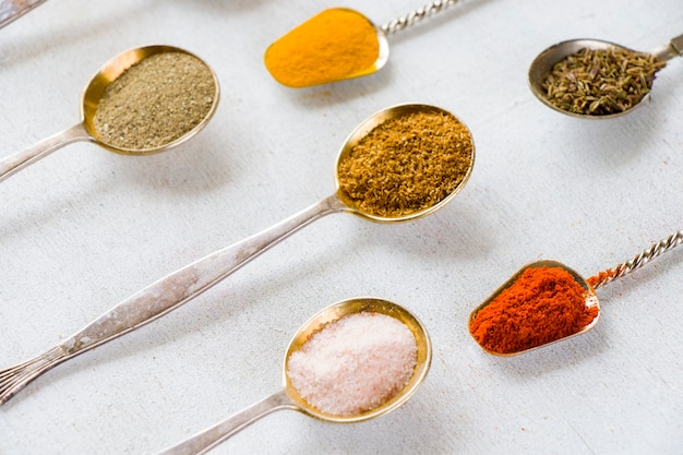 Variation of spices on the vintage silver spoons, all spices on the table, colorful food  