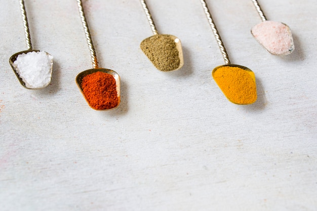 Variation of spices on the vintage silver spoons, all spices on the table, colorful food  