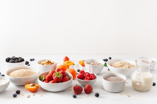 Variaty of raw cereals, fruits and nuts for breakfast. Oatmeal flakes and steel cut, barley, walnut, chia, apricot, strawberry. Healthy ingredients