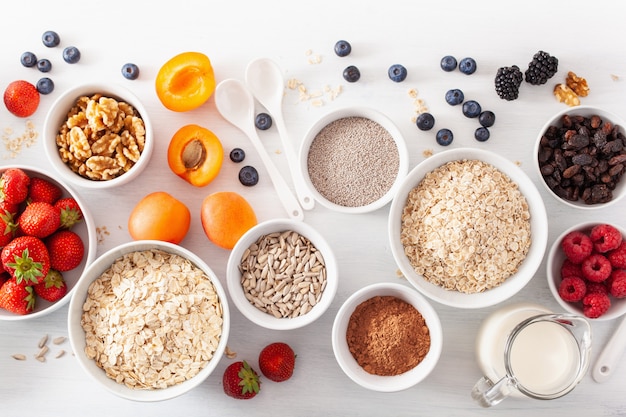 Variaty of raw cereals, fruits and nuts for breakfast. Oatmeal flakes and steel cut, barley, walnut, chia, apricot, strawberry. Healthy ingredients