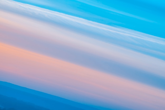 Varicolored gestreepte surrealistische hemel met tinten blauw, cyaan, roze kleuren met kobaltland. Diagonale lijnen van vloeiende wolken.