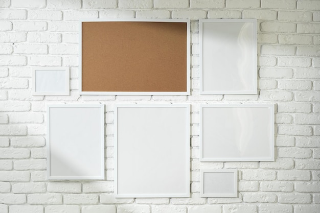 Varied sized photo frames displayed on a white brick wall