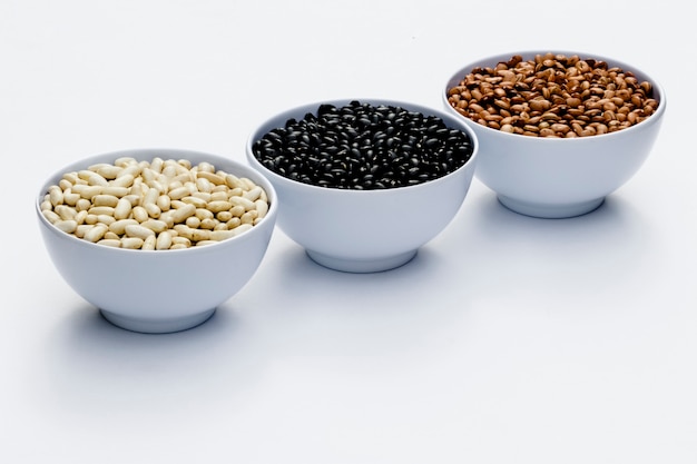 Varieties of beans in bowls, white background