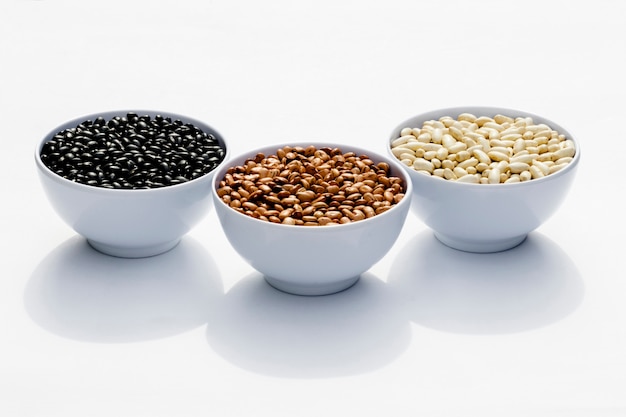 Varieties of beans in bowls, white background