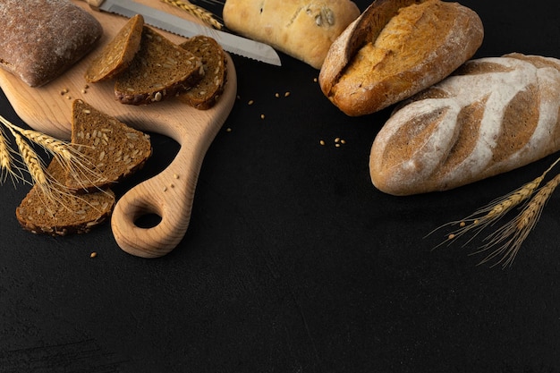 Varieties of glutenfree pastries on a wooden cutting board with a knife on a black background
