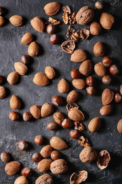 Разновидности орехов: миндаль, фундук и грецкие орехи на темном фоне текстуры