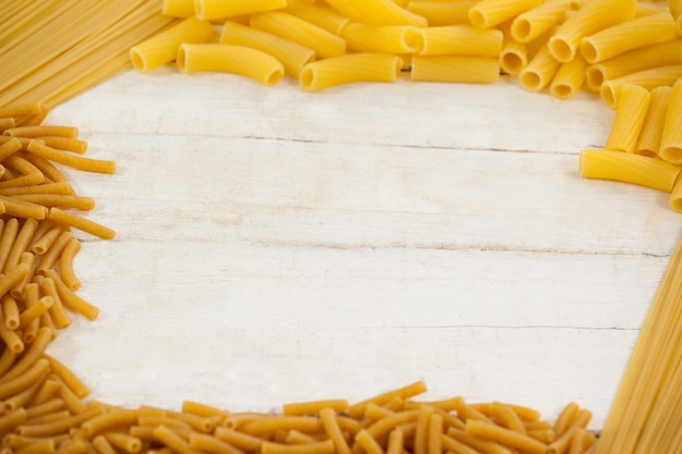 Varieties of pasta forming a frame on white surface