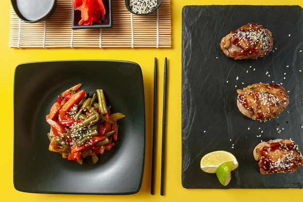 A variety of asian food on a bright yellow background chinese fried vegetables with other asian food