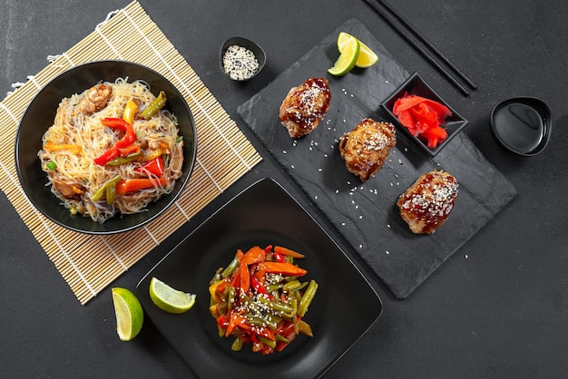 Photo a variety of asian food on a dark concrete background teriyaki chicken stirfried chinese vegetables