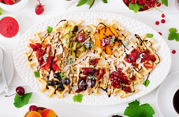 Variety of Belgian wafers with berries, chocolate and syrup.