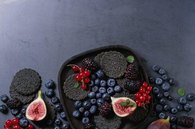 Variety of berries and figs with black crackers