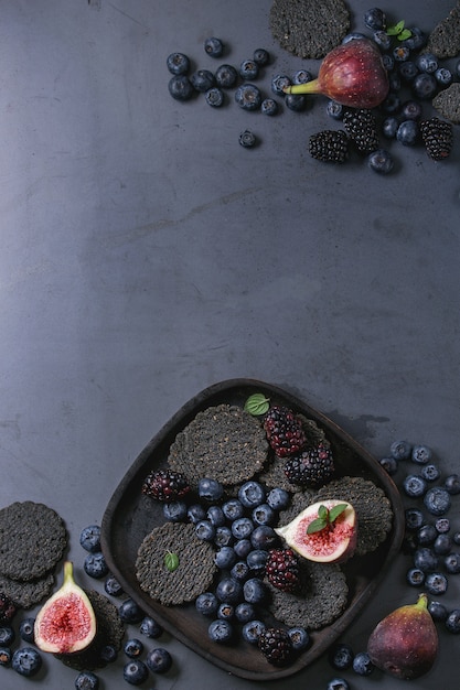 Variety of berries and figs with black crackers