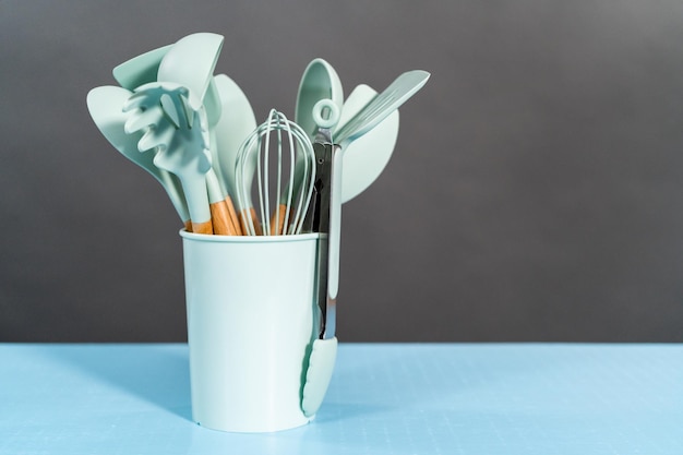 Variety of blue silicone kitchen utensils in a cup.