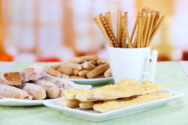 Variety of bread sticks on table on bright background