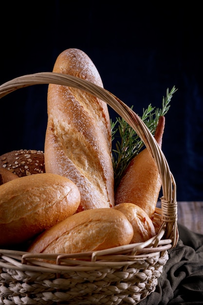 Variety of breads in basket on wooden table in dark