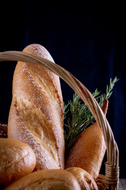 Variety of breads in basket on wooden table in dark