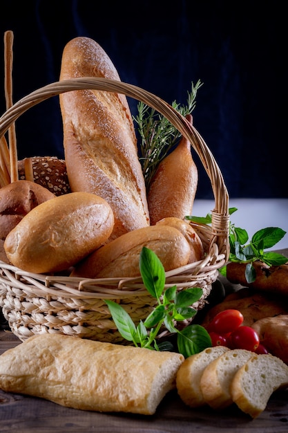 Varietà di pane nel cestino sulla tavola di legno nel buio