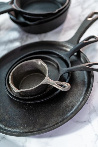 Variety of cast iron frying pans on a marble background.