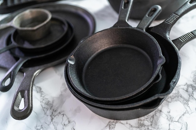 Photo variety of cast iron frying pans on a marble background.