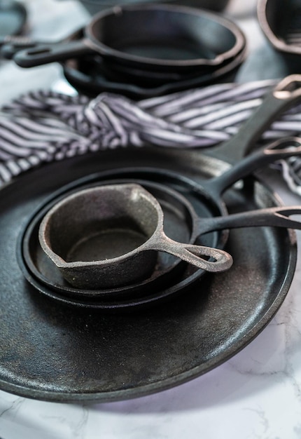 Variety of cast iron frying pans on a marble background.