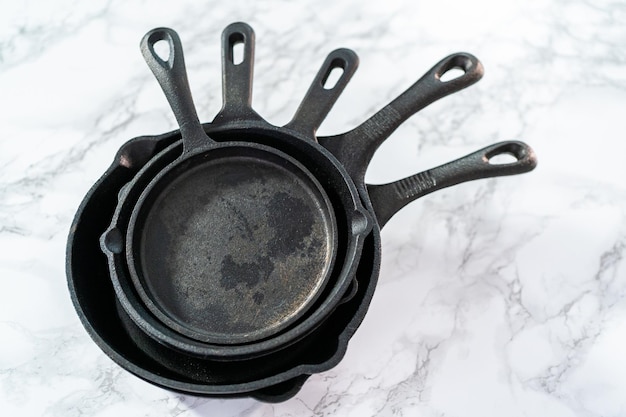 Variety of cast iron frying pans on a marble background.