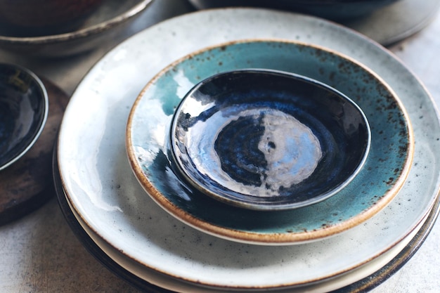 Photo variety of ceramic tableware plates bowls glazed dishes and cutlery on stone table selective focus
