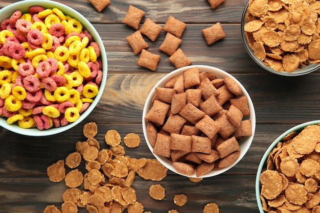 Variety of cereals in blue bowls, quick breakfast on brown wooden background. Top view